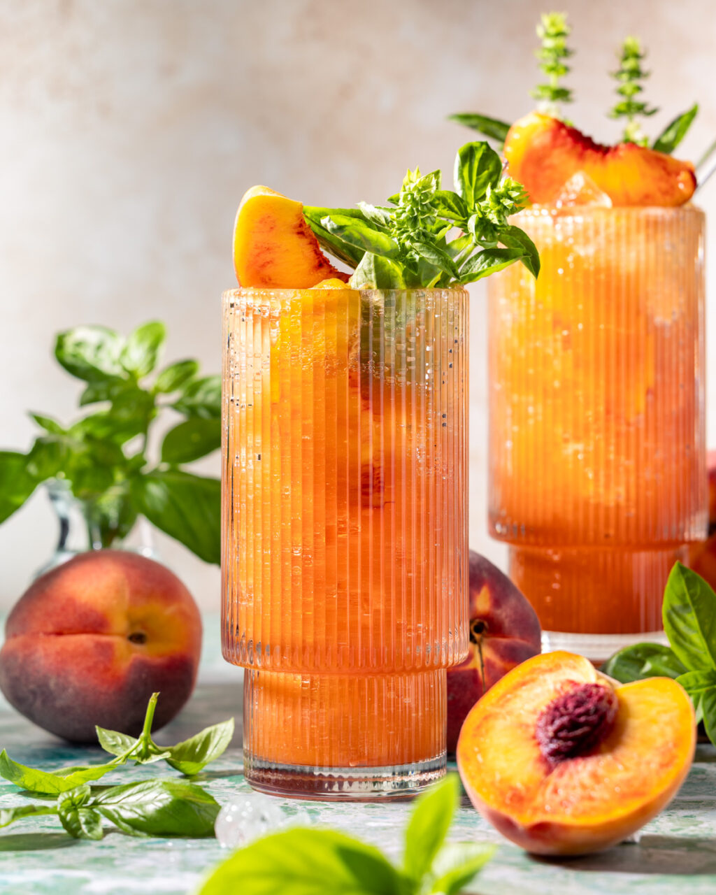Peach Basil Highball made with bourbon, peaches, honey, lemon juice, and fresh basil. Topped off with sparkling water for a refreshing summer cocktail!