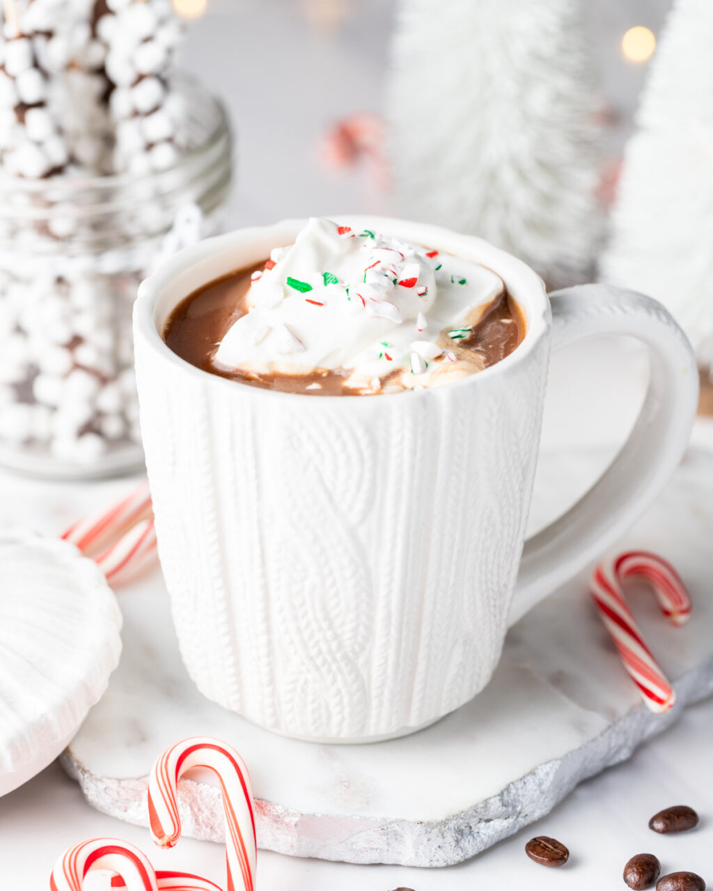 Slow Cooker Peppermint Mocha Hot Chocolate shown in a mug topped with whipped cream and crushed candy canes.