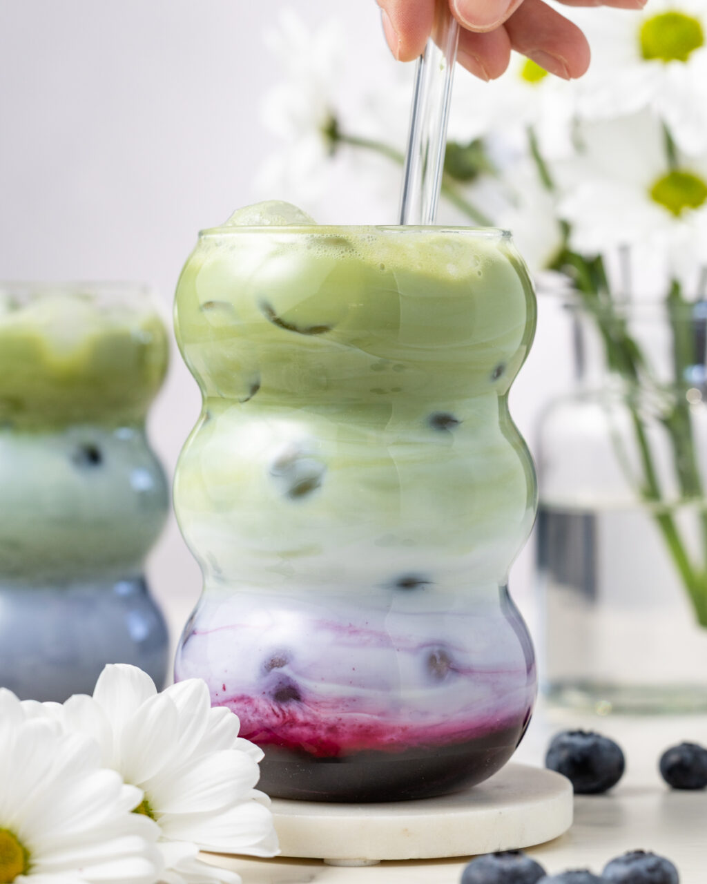 Blueberry Matcha Iced Latte being stirred.