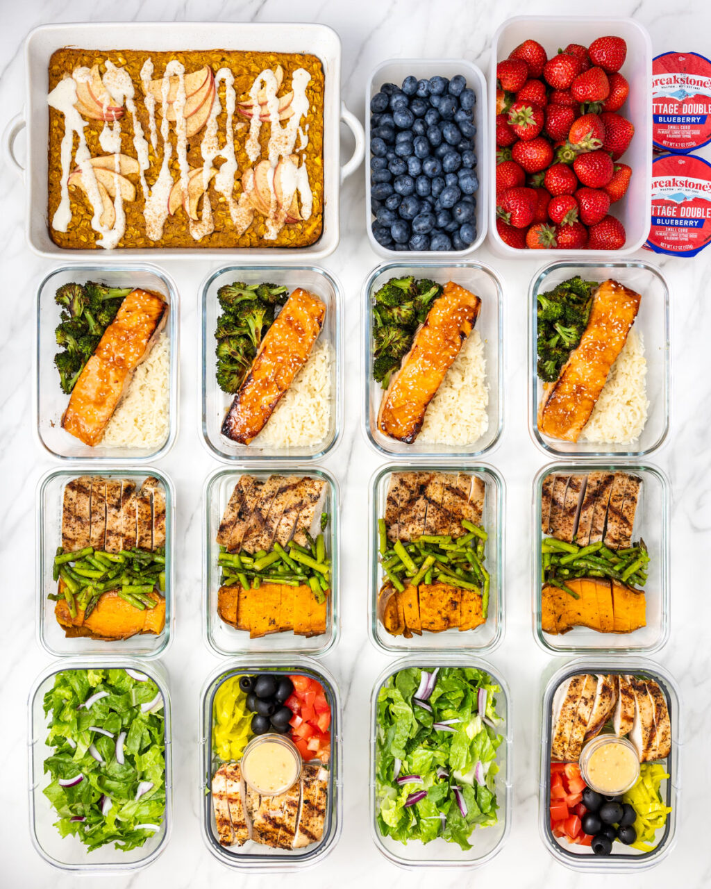 High Protein Weekly Meal Plan. Filled meal prep containers with food for 1 week aligned on marble counter.